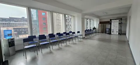 Auditorio con ventanales y sillas azules en fila.