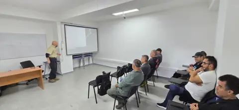 Clase teórica con instructor frente a alumnos sentados.