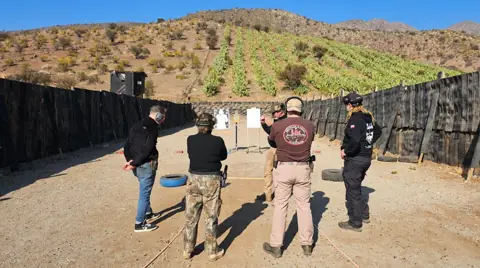 Alumnos e instructores en la línea de tiro del polígono al aire libre.