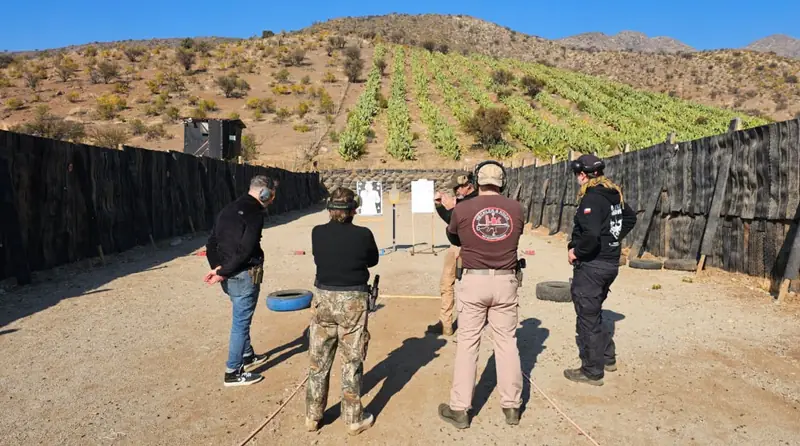 Alumnos e instructores en la línea de tiro del polígono al aire libre.