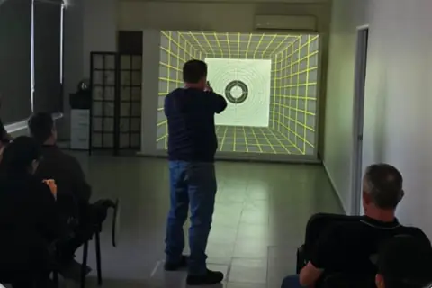 Alumno apunta a la diana proyectada en el polígono virtual.