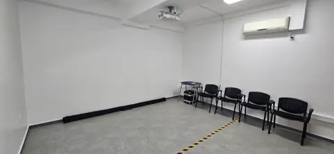 Sala 2, pequeña, con un proyector en el techo y sillas negras al fondo.