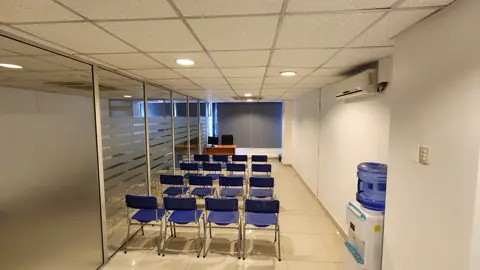Sala con tabique de vidrio y sillas azules.