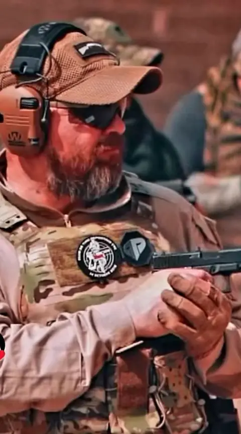 Tirador con gorra, gafas y protección auditiva apunta una pistola.
